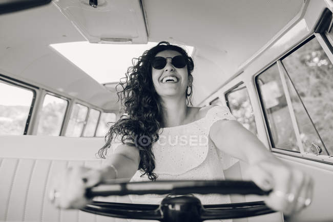 Смеющаяся молодая женщина в солнечных очках за рулем ретро автомобиля — стоковое фото
