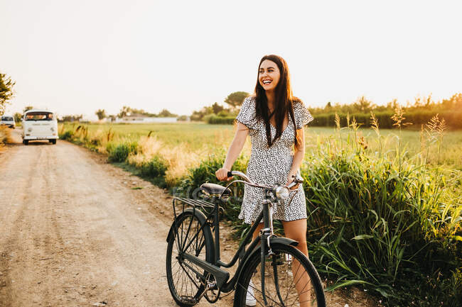 Woman with bicycle in countryside — Stock Photo