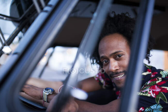 Hermoso afro hombre disfruta del viaje en su camioneta vintage con algunos amigos - foto de stock