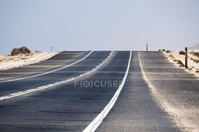 Estrada em linha reta no deserto de Fuerteventura, Ilhas Canárias — Fotografia de Stock