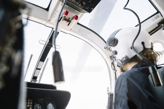 Female pilot in helmet sitting and operating in helicopter — Stock Photo
