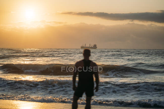 Строгий старик наблюдает за закатом на пляже — стоковое фото