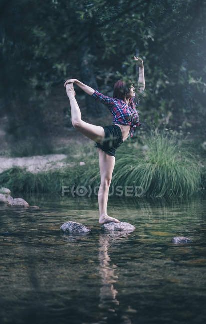 Червоне волосся дівчина виконує вправи біля річки — стокове фото