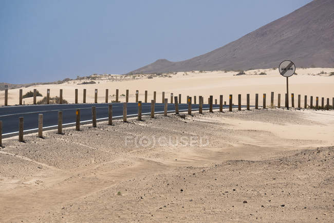 Estrada com sinal e montanhas no deserto de Fuerteventura, Ilhas Canárias — Fotografia de Stock