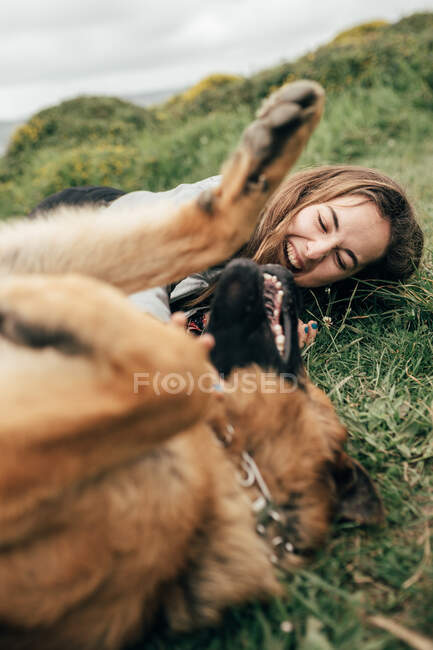 Young woman petting dog in nature — Stock Photo