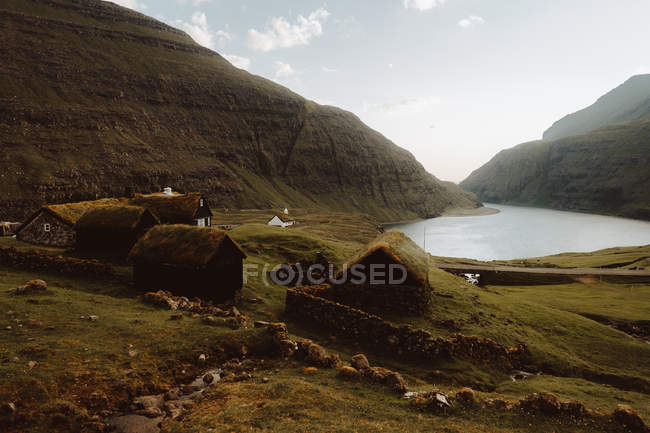 Stone rural houses with grass on roofs in hillside at lake on Feroe Islands — Stock Photo