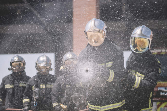 Pompieri di lavoro gettare acqua con tubo. — Foto stock