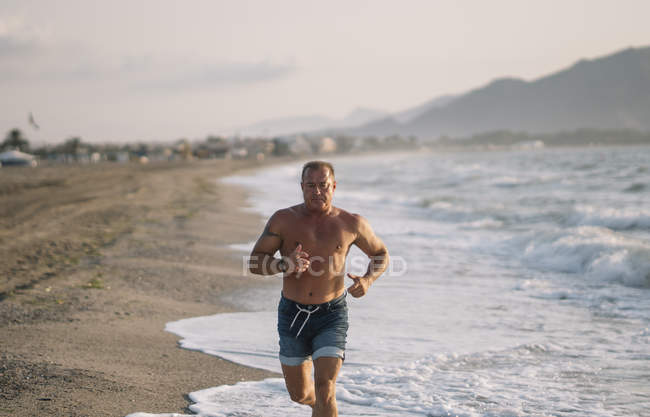 Forte vecchio fa esercizio sulla spiaggia — Foto stock
