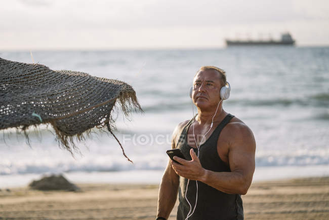Idoso ouve música na praia — Fotografia de Stock