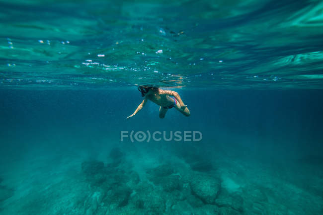Garçon méconnaissable plongée avec tuba dans l'eau de mer sombre — Photo de stock