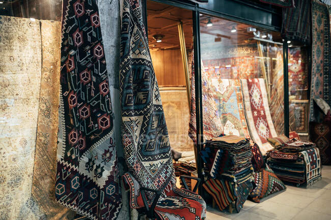 Различные декоративные ковры, лежащие рядом с небольшим магазином на рынке в Стамбуле, Турция — стоковое фото