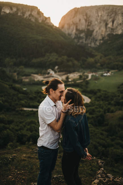 Bonito casal abraçando, beijando e testa endurecedora, enquanto em pé no fundo do belo vale e montanhas — Fotografia de Stock