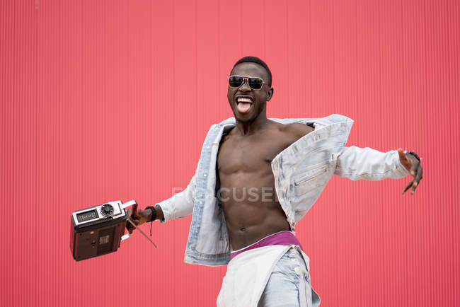 Uomo afroamericano che balla con dispositivo radio vintage su sfondo rosso — Foto stock