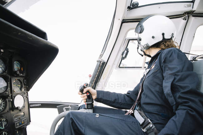 Female pilot in helmet sitting in helicopter and operating — Stock Photo