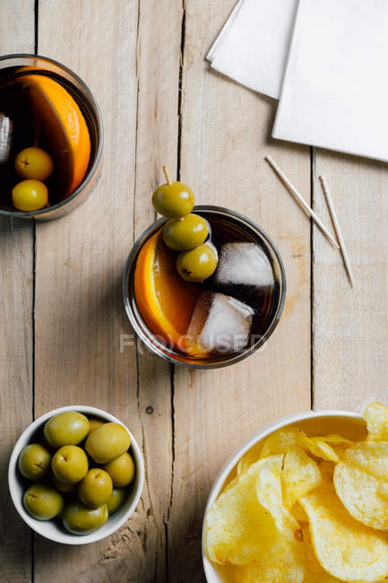 Cocktails and snacks served on wooden table — Stock Photo