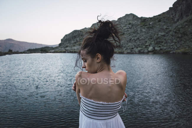 Giovane donna in abito elegante in piedi vicino lago increspatura — Foto stock
