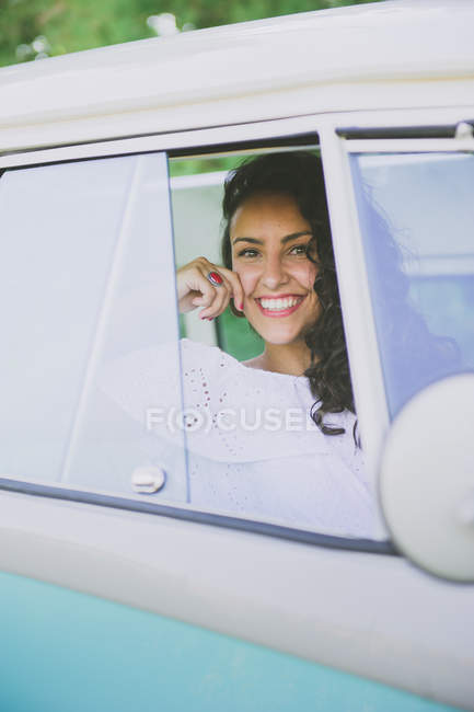 Joyeux jeune femme regardant caméra à l'intérieur de la voiture — Photo de stock