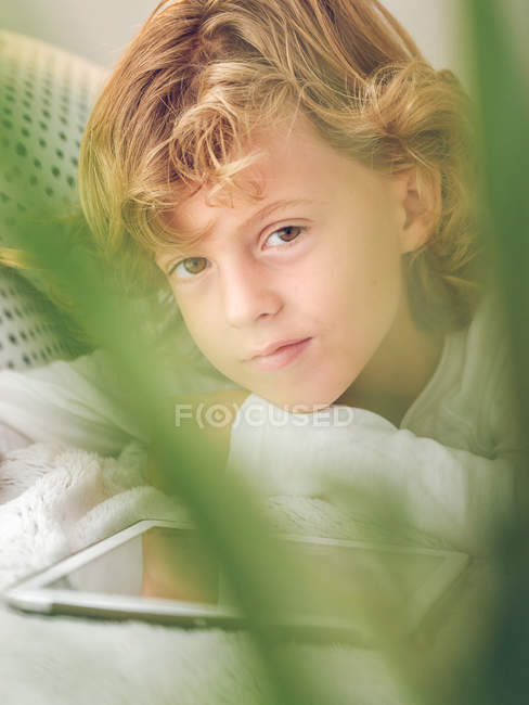Портрет хлопчика з цифровим планшетом, що лежить на дивані — стокове фото