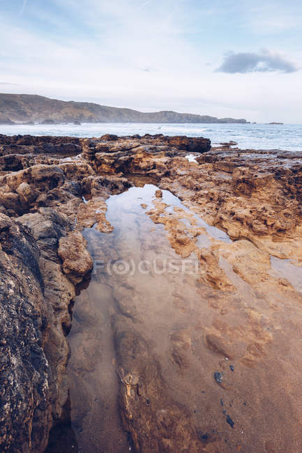 Ruhiges Meerwasser in der Nähe einer kleinen Bucht nahe der steinigen Küste an sonnigen Tagen in Asturien, Spanien — Stockfoto