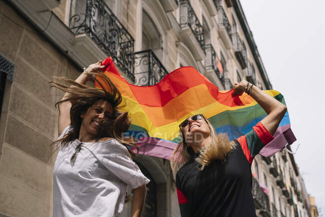 Пара лесбійок з гей-прайд прапором на вулиці Мадрида — стокове фото