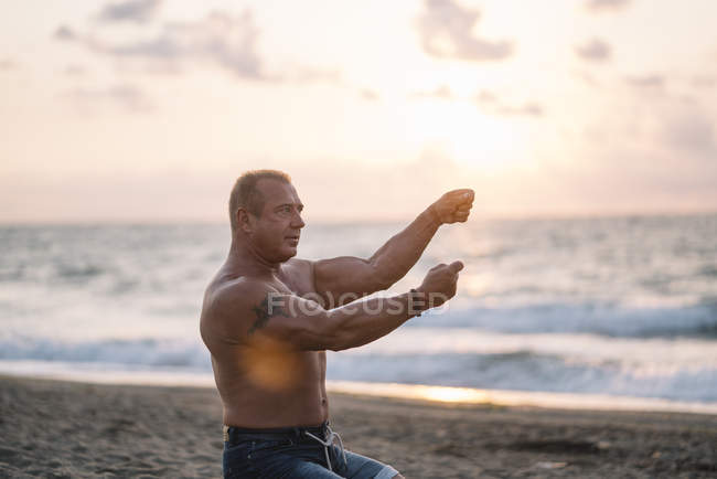 Сильний старий робить вправи на пляжі — стокове фото