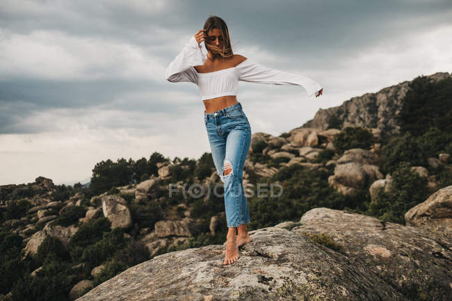 Femme en jeans marchant sur le rocher — Photo de stock