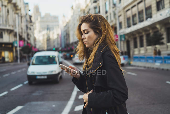 Жінка використовує смартфон на дорозі в місті — стокове фото