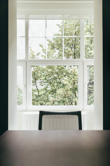 Комфортне крісло і стіл, що стоїть біля красивого вікна в стильній кімнаті — стокове фото