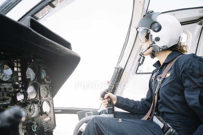 Зосереджена жінка-пілот сидить і працює на вертольоті — стокове фото