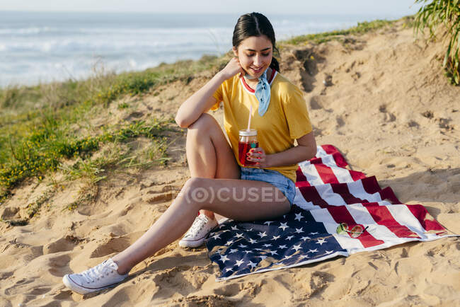 Menina casual com bebida na areia — Fotografia de Stock