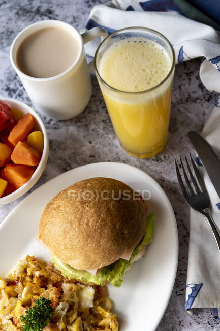 Гамбургер и омлет на тарелке с фруктами и соком — стоковое фото