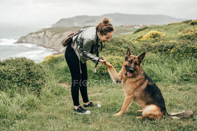 Jeune femme caressant chien dans la nature — Photo de stock