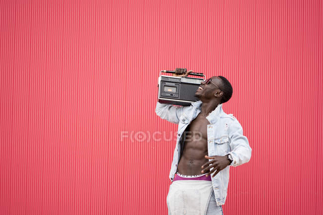 Uomo afroamericano sorridente con dispositivo radio vintage su sfondo rosso — Foto stock