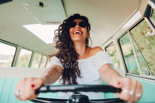 Сміється молода жінка в сонцезахисних окулярах за кермом ретро-автомобіль — стокове фото