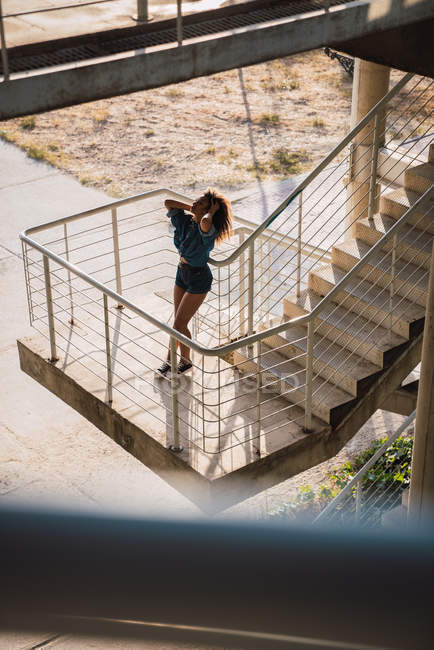 Woman leaning on railing of staircase outdoors — Stock Photo