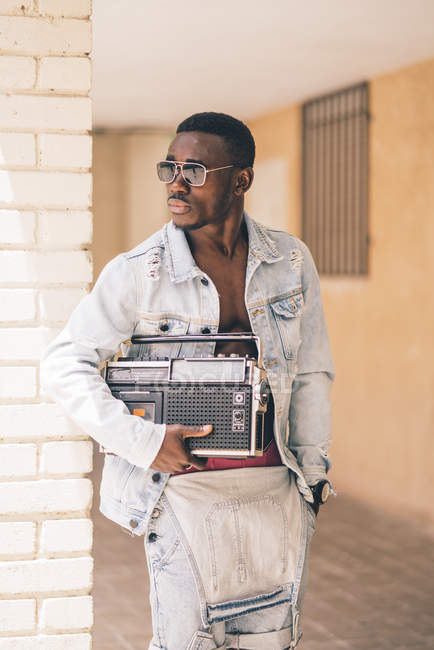 Thoughtful black man in sunglasses holding vintage radio device outdoors — Stock Photo