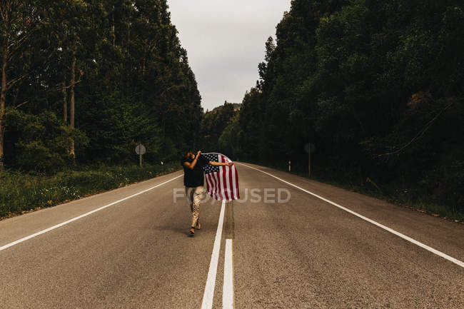 Mann mit US-Fahne läuft Straße entlang — Stockfoto