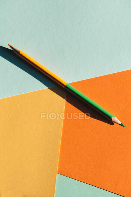 Lápiz de color de doble extremo, sobre fondo geométrico azul claro y naranja, volver al concepto de la escuela - foto de stock