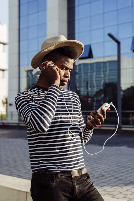 Homme noir dans les écouteurs en utilisant un smartphone — Photo de stock