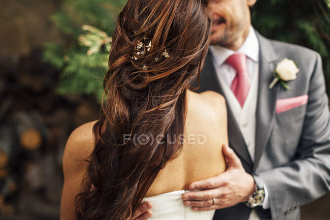 Hand of unrecognizable groom embracing bride in white dress. — Stock Photo