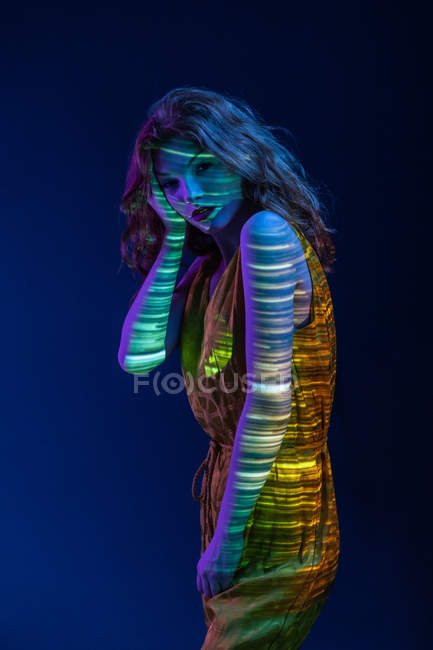 Retrato de mulher pensativa posando em luz quente no fundo azul escuro — Fotografia de Stock
