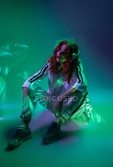 Elegante mulher legal desfrutando de música com fones de ouvido em luz de néon — Fotografia de Stock
