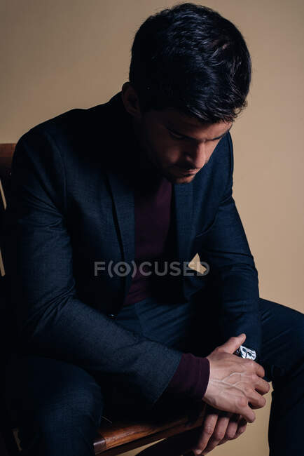 Young thoughtful business man in a studio seating in a chair — Stock Photo