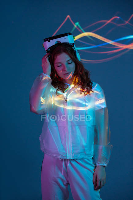 Woman wearing VR glasses in neon light on blue background — Stock Photo