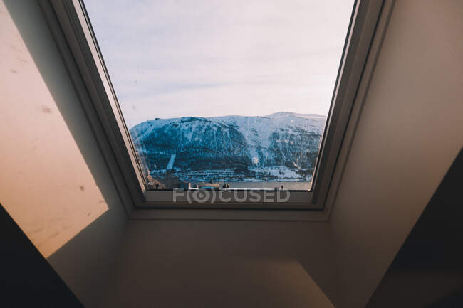 Landschaft verschneiter Berge durch Glasfenster in Mansardendach im Sonnenlicht — Stockfoto