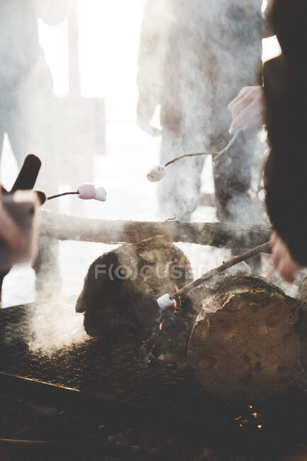Tourists frying marshmallows in fire outdoors — Stock Photo
