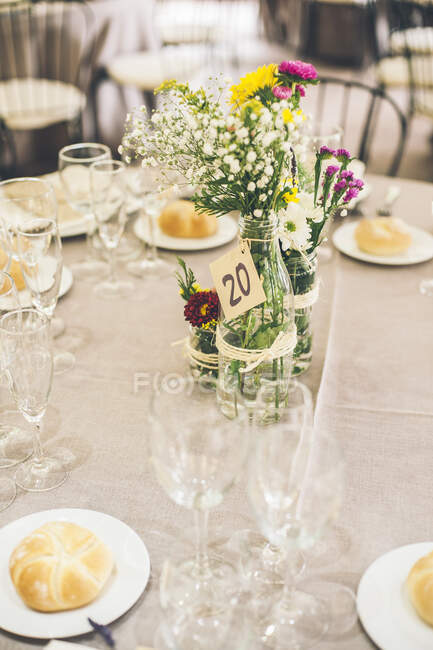 Bright beautiful rustic flowers in bottle on served banquette table. — Stock Photo