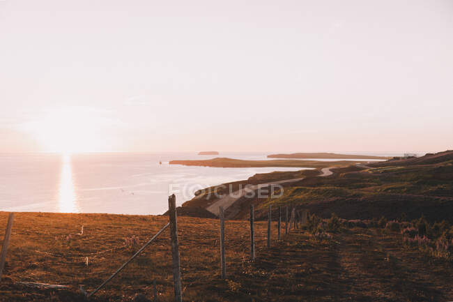 Panoramic view of spacious shoreline with road running away in sunset light glowing in sky — Stock Photo