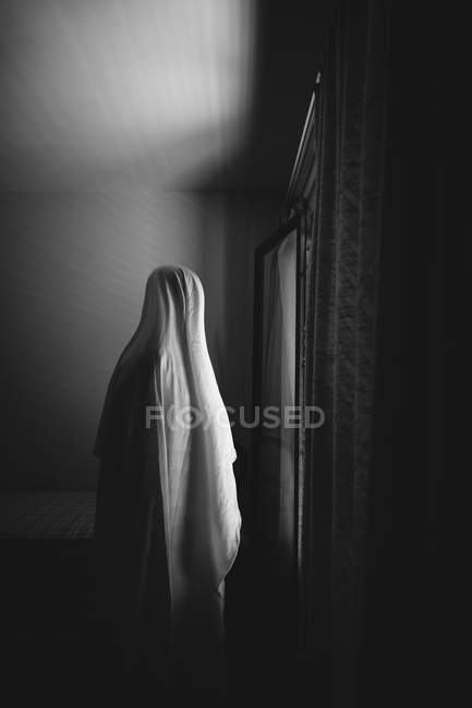 Person disguised as ghost for Halloween standing in dark room — Stock Photo