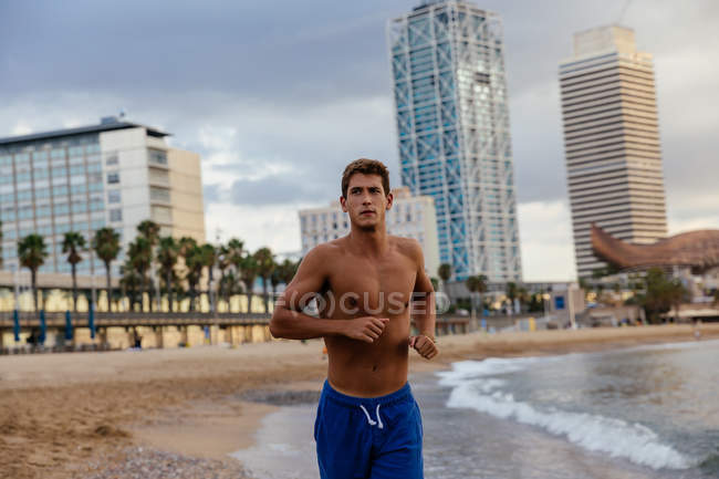 Young man running on the shore — Stock Photo